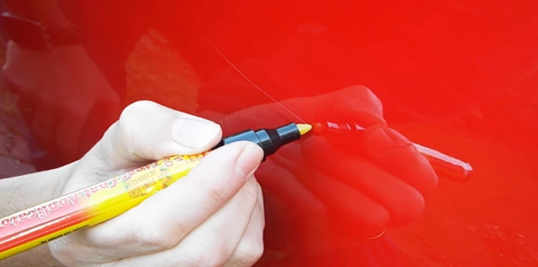 person uses CarScratcher Pencil on red car